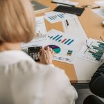Profissionais analisam gráficos financeiros e usam calculadoras durante uma reunião de planejamento em um escritório.