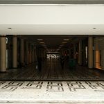 Corredor amplo de um shopping center moderno, com pessoas caminhando entre áreas comerciais.