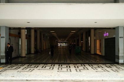 Corredor amplo de um shopping center moderno, com pessoas caminhando entre áreas comerciais.