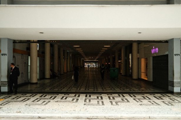 Corredor amplo de um shopping center moderno, com pessoas caminhando entre áreas comerciais.