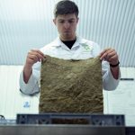 Cientista examina um material biodegradável em um laboratório de pesquisa e inovação sustentável.