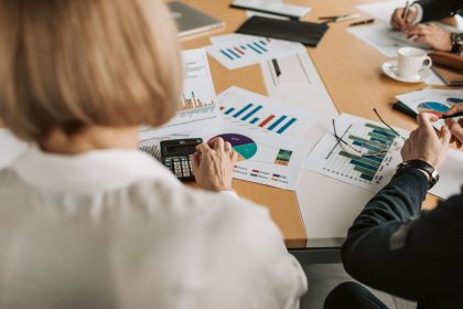 Profissionais analisam gráficos financeiros e usam calculadoras durante uma reunião de planejamento em um escritório.