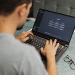 Profissional trabalha em um laptop com uma interface de inteligência artificial em um escritório moderno.